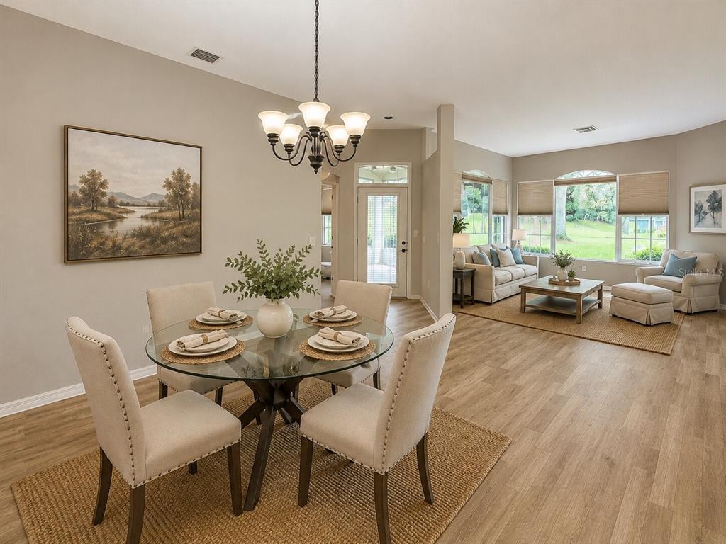 A dining area with a glass table and chairs opens into a bright living room — 39905 BAYVIEW DRIVE, LADY LAKE, FL