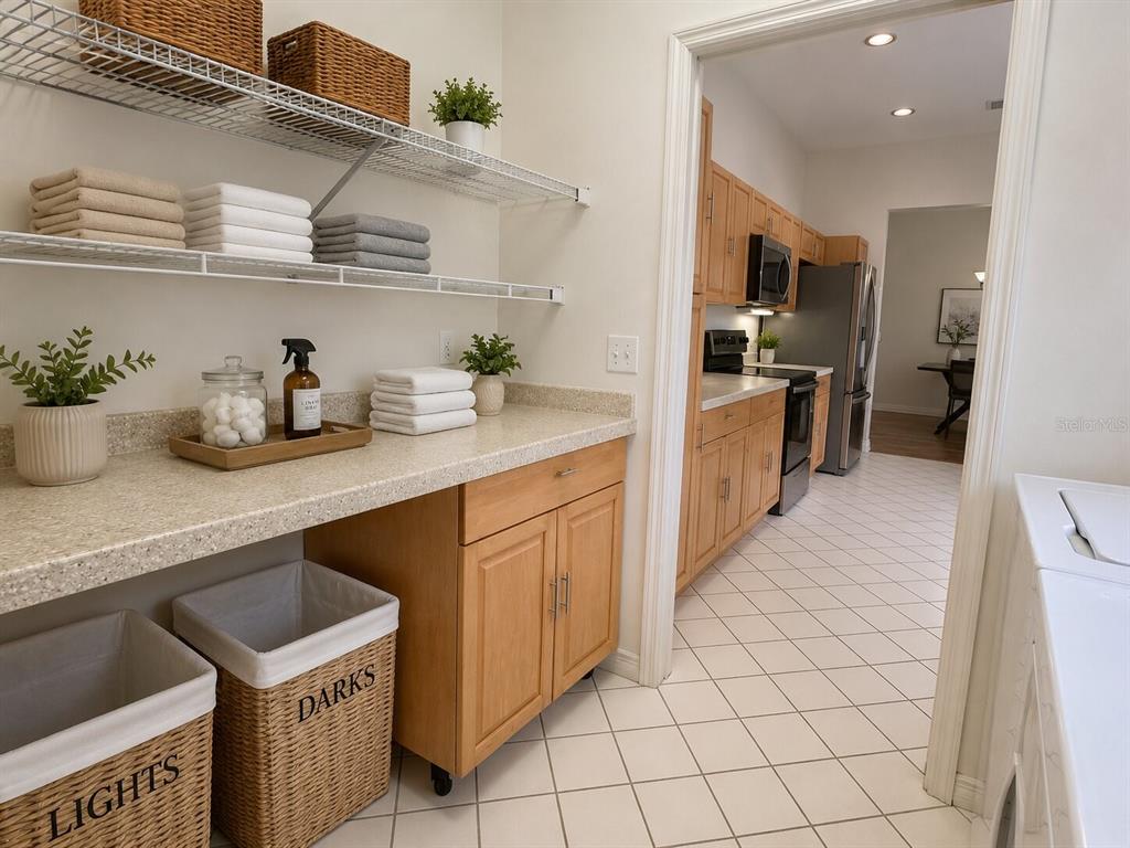A laundry room with wire shelving, light wood cabinets, and wicker baskets leads into a kitchen — 39905 BAYVIEW DRIVE, LADY LAKE, FL