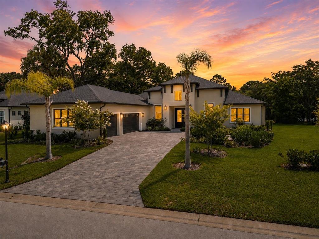 A modern single-story house with a paved driveway, two-car garage, and palm trees in front — 17 OLD OAK DRIVE N, PALM COAST, FL