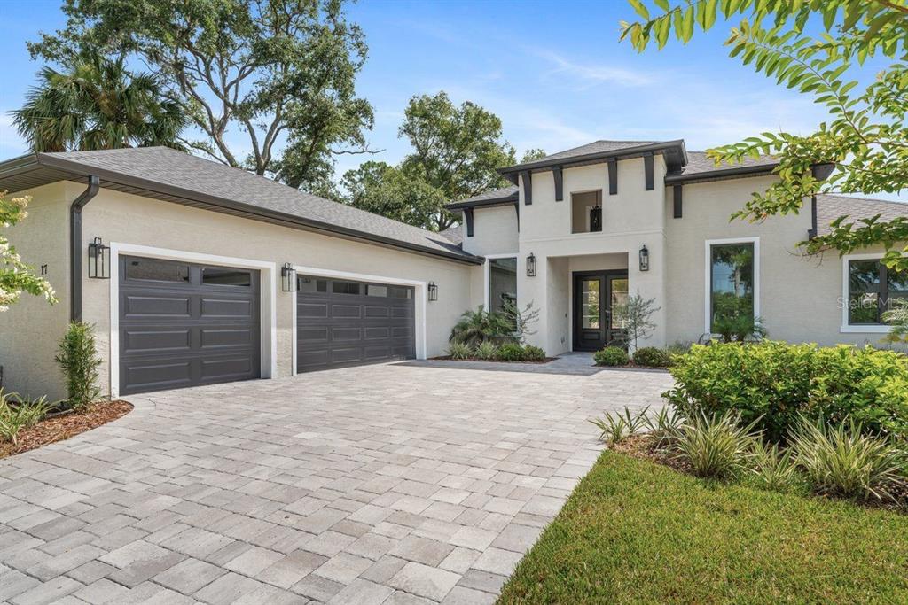 A modern house exterior features a paved driveway, a three-car garage, and a covered entryway — 17 OLD OAK DRIVE N, PALM COAST, FL