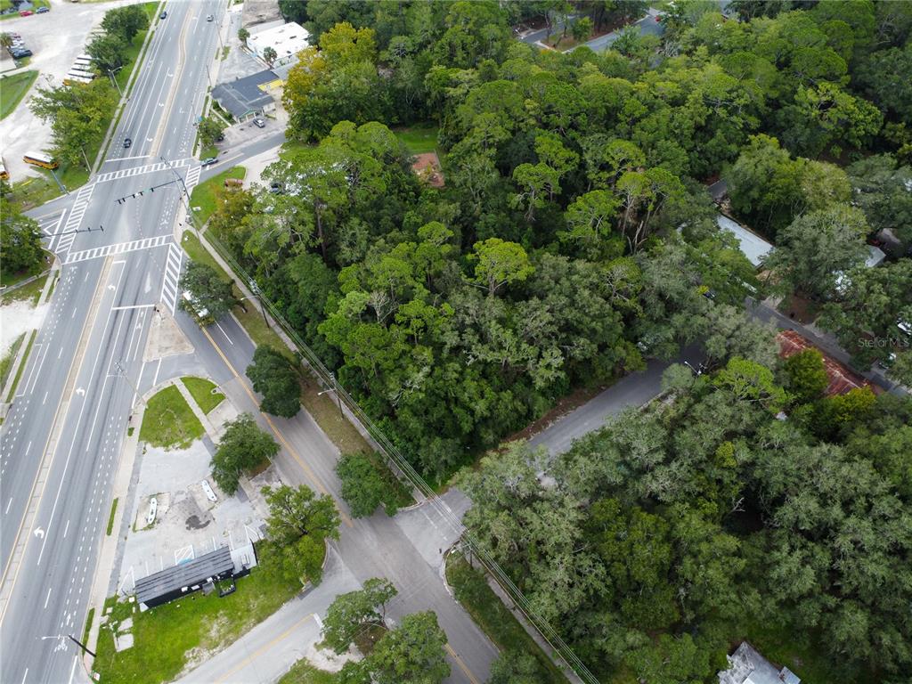 An aerial view shows a wooded lot situated between a multi-lane road and a side street — 1715 SE 4TH AVENUE, GAINESVILLE, FL