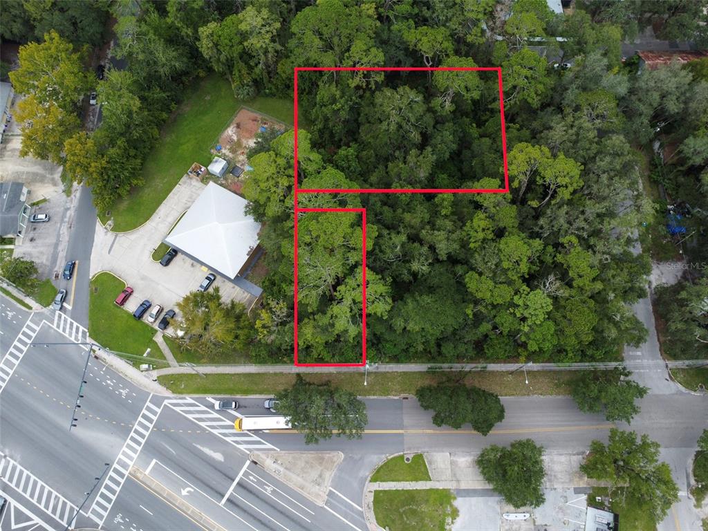 An aerial view shows a wooded lot outlined in red next to a commercial building — 1715 SE 4TH AVENUE, GAINESVILLE, FL
