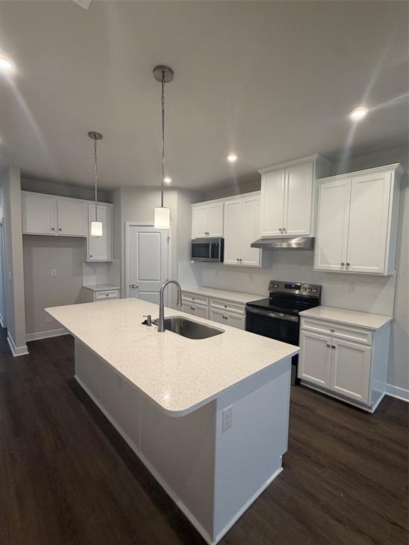 An open-concept living area features dark wood-look flooring, recessed lighting, and a white kitchen island — 18732 HIGHLAND DEW STREET, SPRING HILL, FL