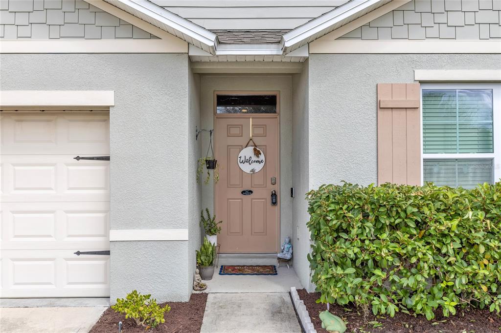 The exterior of a house features a tan front door, a garage, and a landscaped yard — 319 CHARLES DRIVE, DELAND, FL