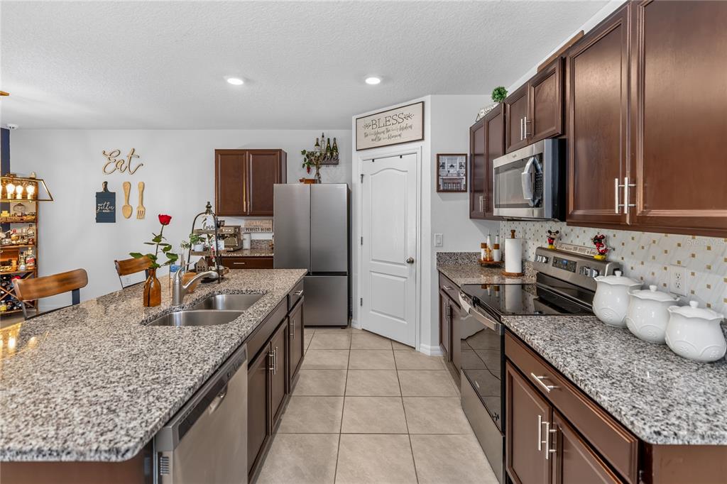 A kitchen features dark wood cabinets, granite countertops, stainless steel appliances, and tile flooring — 319 CHARLES DRIVE, DELAND, FL