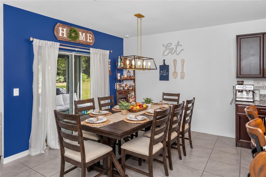 A dining room features a wooden table, six chairs, a blue accent wall, and tile flooring — 319 CHARLES DRIVE, DELAND, FL
