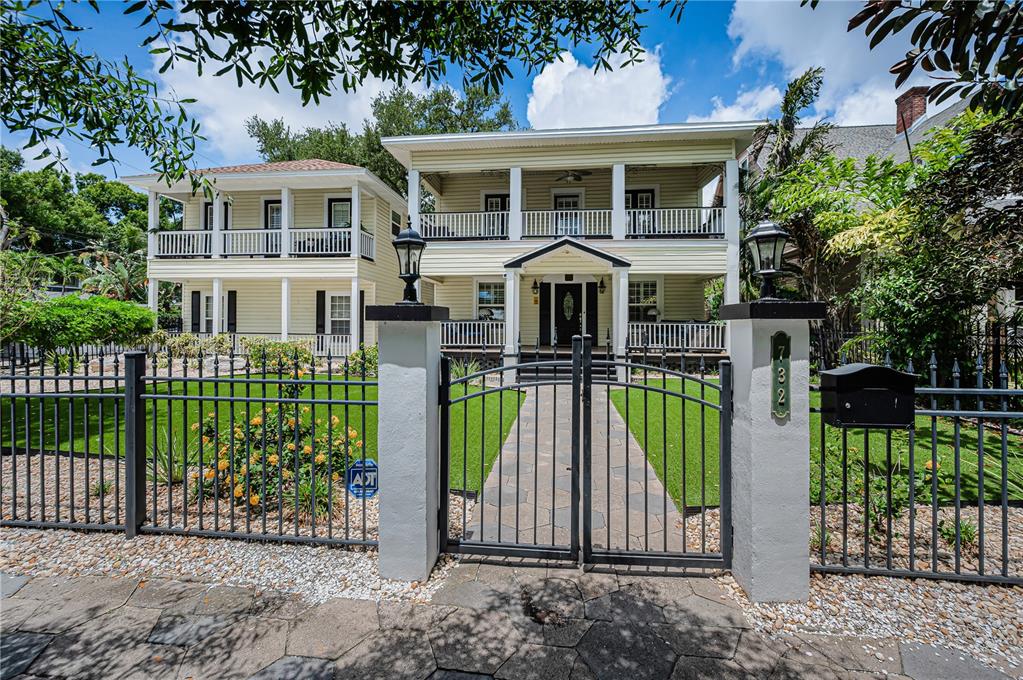A two-story house with a double-decker porch sits behind a black metal fence — 732 and 732 1/2 NE OAK STREET, ST PETERSBURG, FL