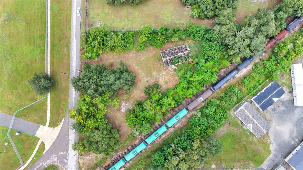 An aerial view shows a train passing by a wooded lot with a dilapidated structure — 3852 RADFORD ROAD, BARTOW, FL
