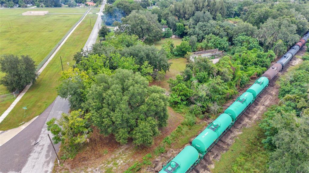 An aerial view shows a freight train passing through a wooded area next to a road — 3852 RADFORD ROAD, BARTOW, FL