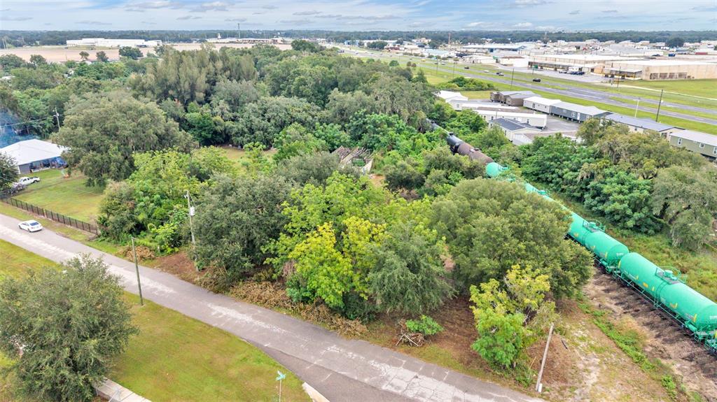 An aerial view shows a wooded lot adjacent to a road and a freight train — 3852 RADFORD ROAD, BARTOW, FL