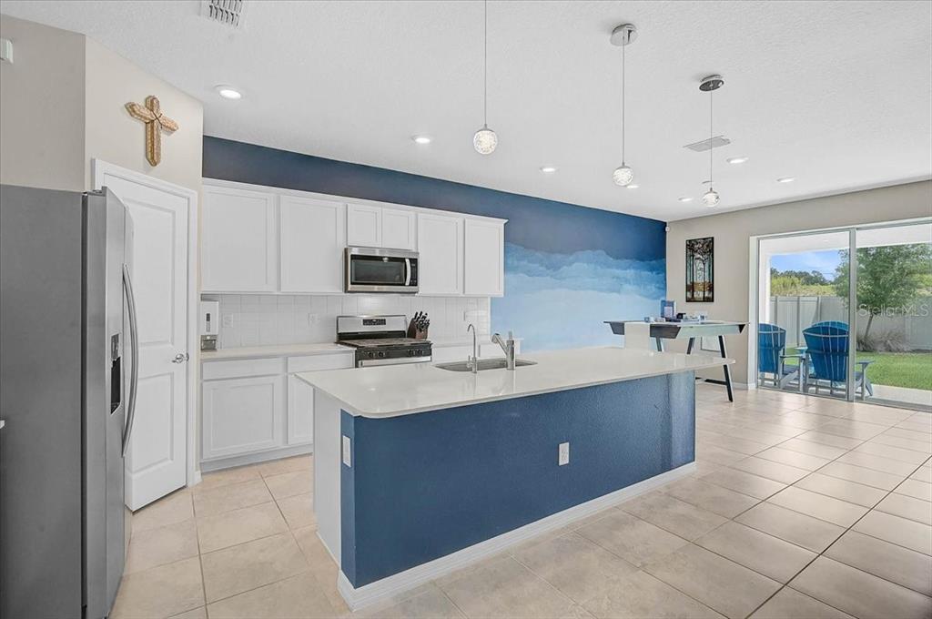A kitchen features white cabinets, a blue accent wall, and a large central island — 3110 61ST DRIVE E, ELLENTON, FL