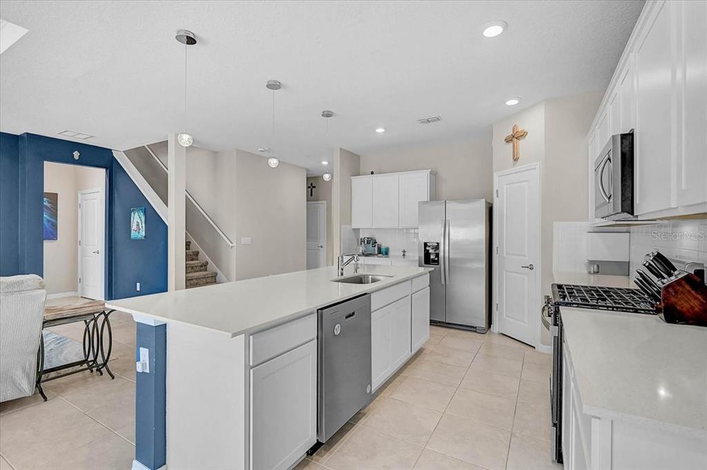 A modern kitchen features a large white island, stainless steel appliances, and white cabinetry — 3110 61ST DRIVE E, ELLENTON, FL