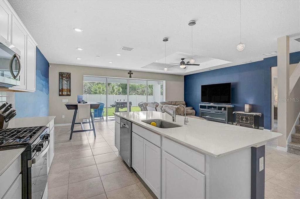 A kitchen with a large white island overlooks a living area with blue walls — 3110 61ST DRIVE E, ELLENTON, FL