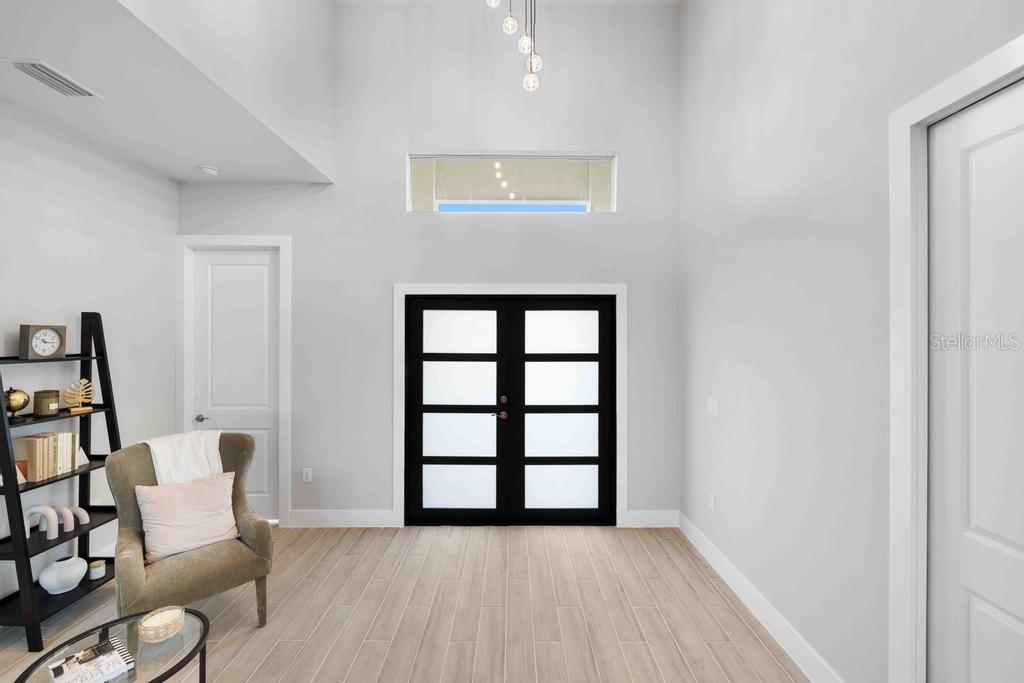 A bright room features high ceilings, a black-framed double door, and light wood-look flooring — 38 LARK DRIVE, PLACIDA, FL