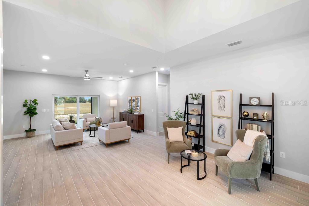 A bright, open-concept living room features light wood-look tile flooring and high vaulted ceilings — 38 LARK DRIVE, PLACIDA, FL