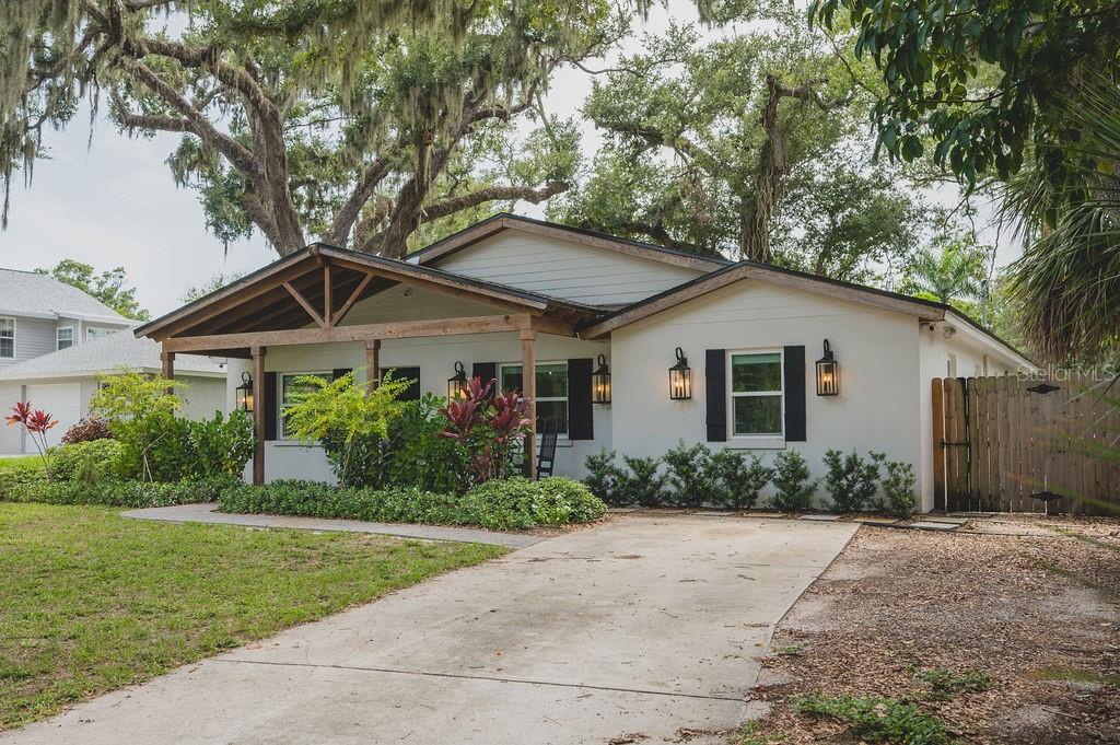A single-story house with a wooden porch, white stucco exterior, and black window shutters — 216 18TH STREET E, BRADENTON, FL