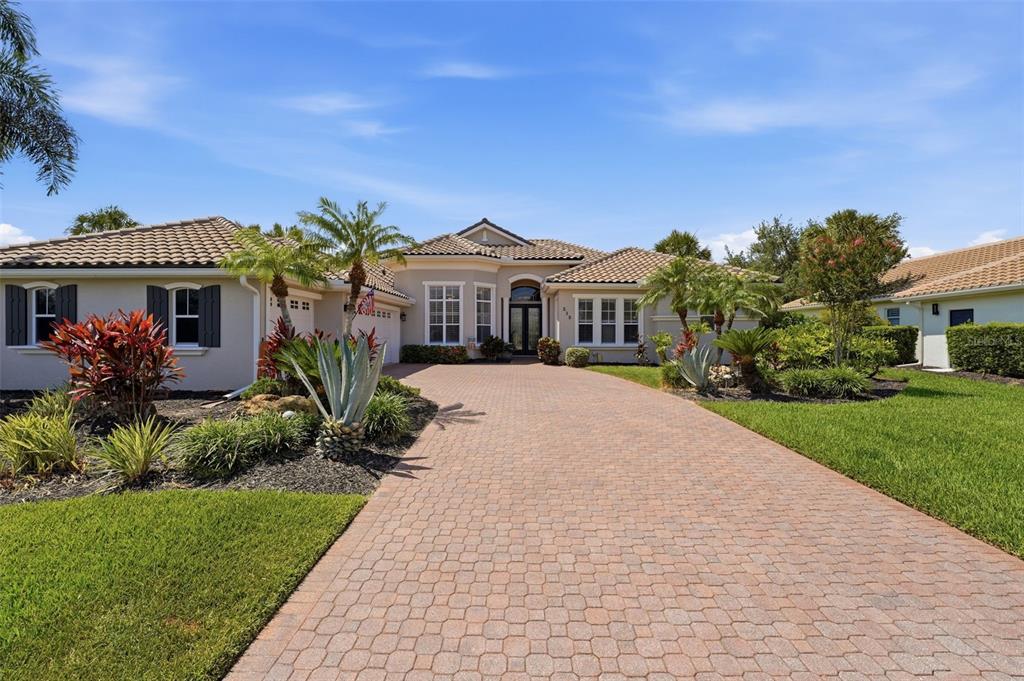 A single-story house with a paved driveway, a three-car garage, and palm trees — 515 SAND CRANE COURT, BRADENTON, FL
