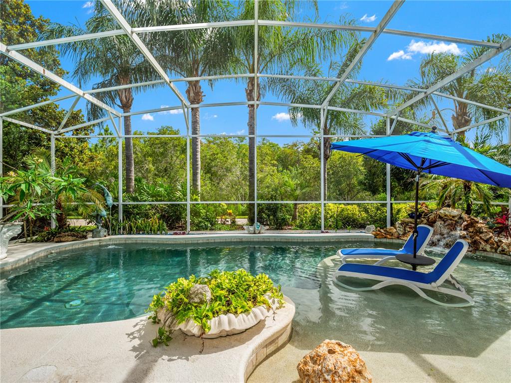 A screened-in swimming pool features a tanning ledge with lounge chairs and a blue umbrella — 11800 ZELKOVA LANE, ORLANDO, FL
