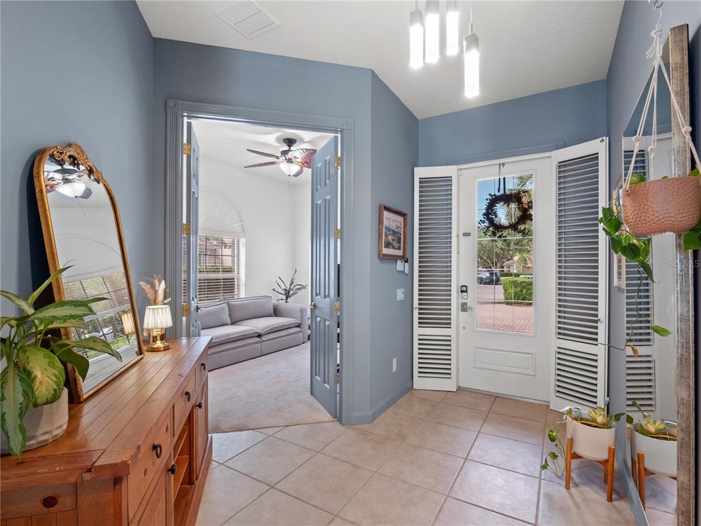 A tiled entryway features blue walls, a wooden console table, and a glass-paneled front door — 11800 ZELKOVA LANE, ORLANDO, FL