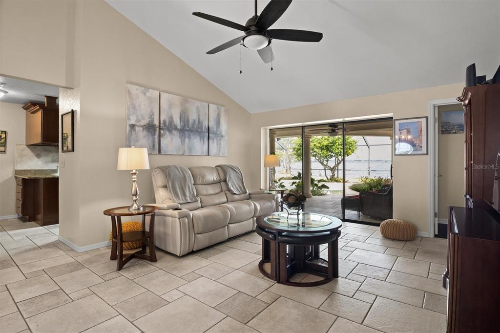 A dining area with a wooden table and chairs sits before a living room with views — 926 VAN DRIVE, AUBURNDALE, FL