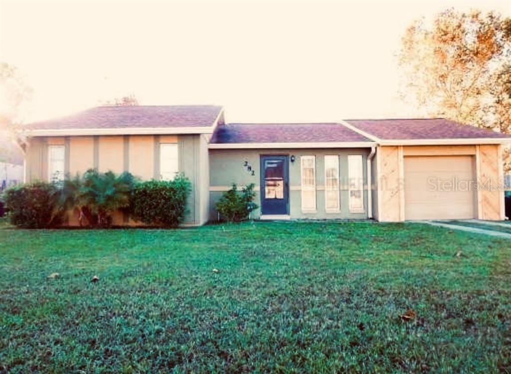 A single-story house with a green exterior, a front door, and an attached garage — 282 SEAL STREET, KISSIMMEE, FL