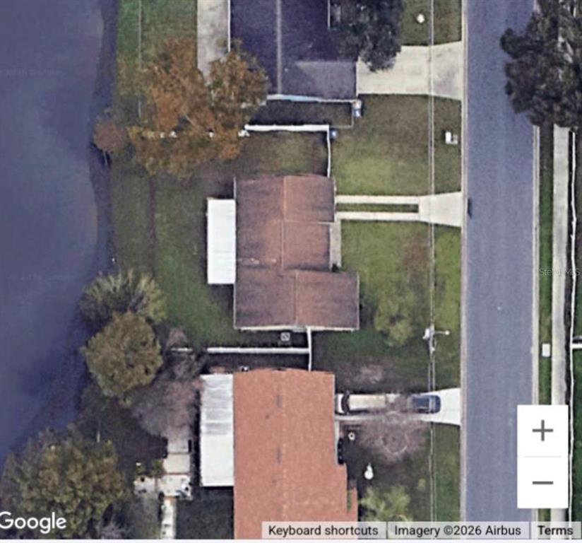 This aerial satellite view shows two adjacent residential houses with driveways and backyard water access — 282 SEAL STREET, KISSIMMEE, FL