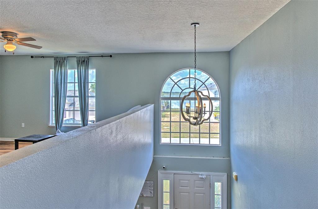 An elevated view of a foyer with a chandelier, arched window, and a loft railing — 169 VISTA VIEW AVENUE, EAGLE LAKE, FL