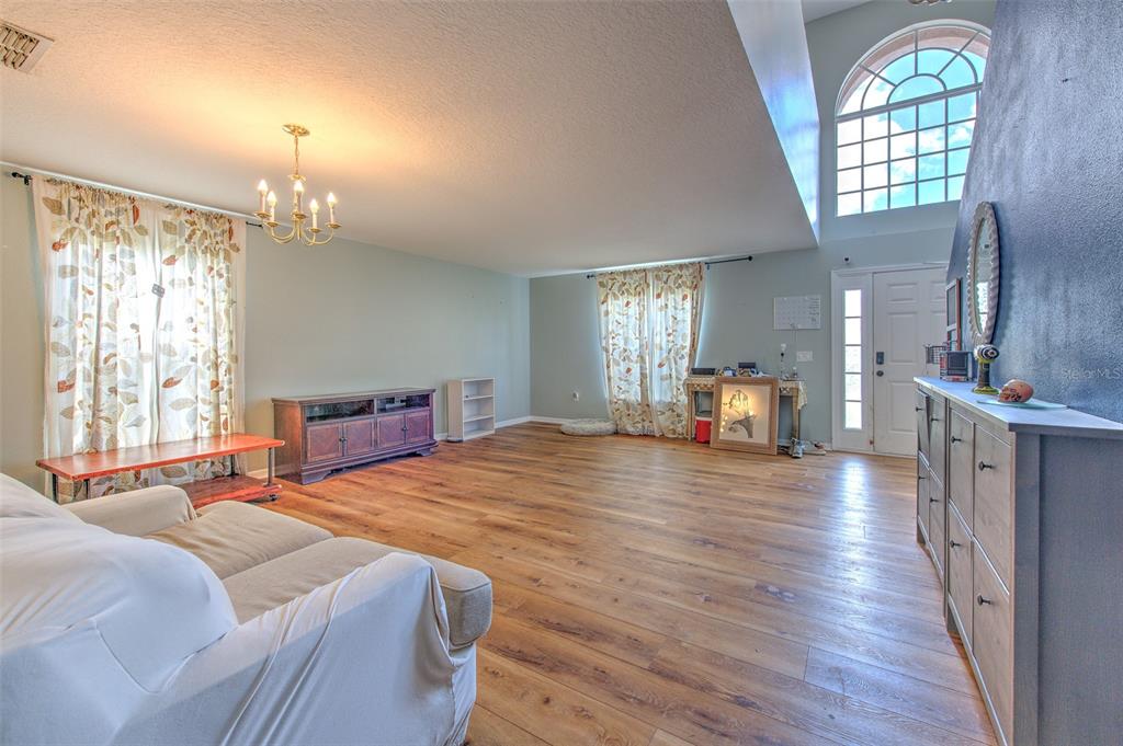 A living room with light wood flooring, a white sofa, and a large arched window — 169 VISTA VIEW AVENUE, EAGLE LAKE, FL