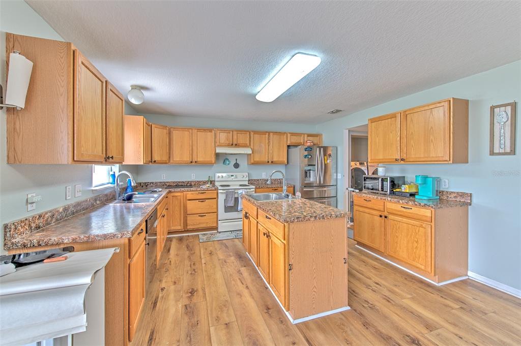 A kitchen features wood cabinets, laminate countertops, a center island, and wood-look flooring — 169 VISTA VIEW AVENUE, EAGLE LAKE, FL