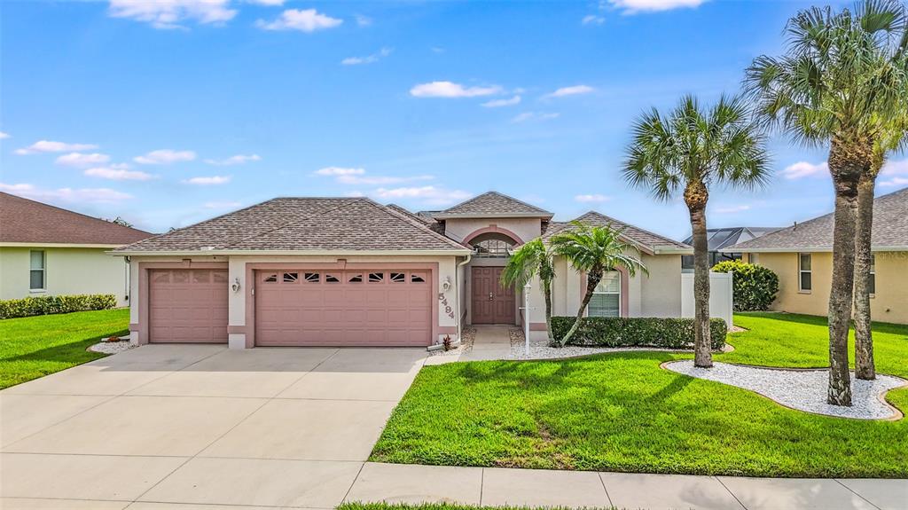 A single-story suburban house with a two-car garage, palm trees, and a manicured lawn — 5494 SABAL TRACE DRIVE, NORTH PORT, FL
