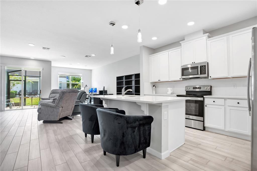 A kitchen with white cabinets and a center island opens to a living area — 4835 JACKSTAFF WAY, OVIEDO, FL
