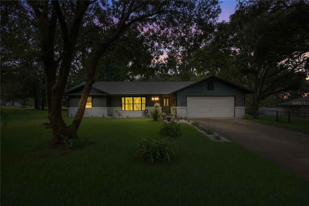 A single-story house with a two-car garage and a large front lawn at dusk — 6000 SW 109TH PLACE, OCALA, FL