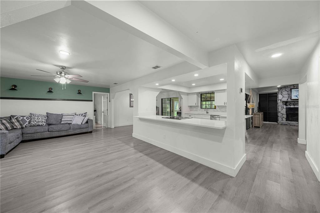 An open-concept living room and kitchen featuring light wood flooring and a white breakfast bar — 6000 SW 109TH PLACE, OCALA, FL
