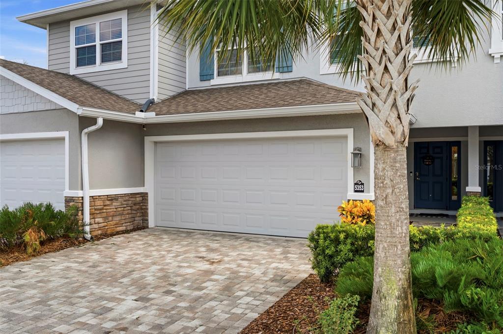 A two-story house exterior features a paved driveway, a garage, and a palm tree — 5353 RIVERWALK PRESERVE DRIVE, NEW PORT RICHEY, FL