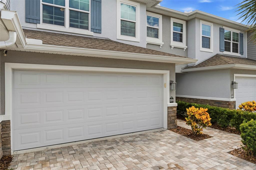 A two-story townhouse exterior with a white garage door and a paved driveway — 5353 RIVERWALK PRESERVE DRIVE, NEW PORT RICHEY, FL