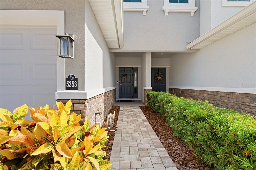 A paved walkway leads to the front entrance of a house with stone veneer siding — 5353 RIVERWALK PRESERVE DRIVE, NEW PORT RICHEY, FL