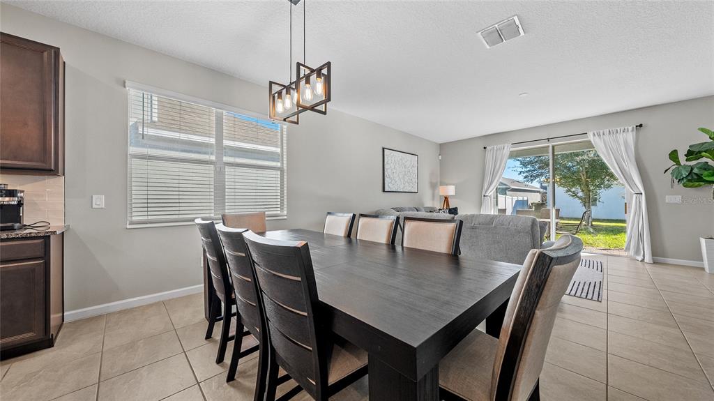 A dining area features a dark wood table, six chairs, and a modern pendant light — 891 JETWAY STREET, ORANGE CITY, FL