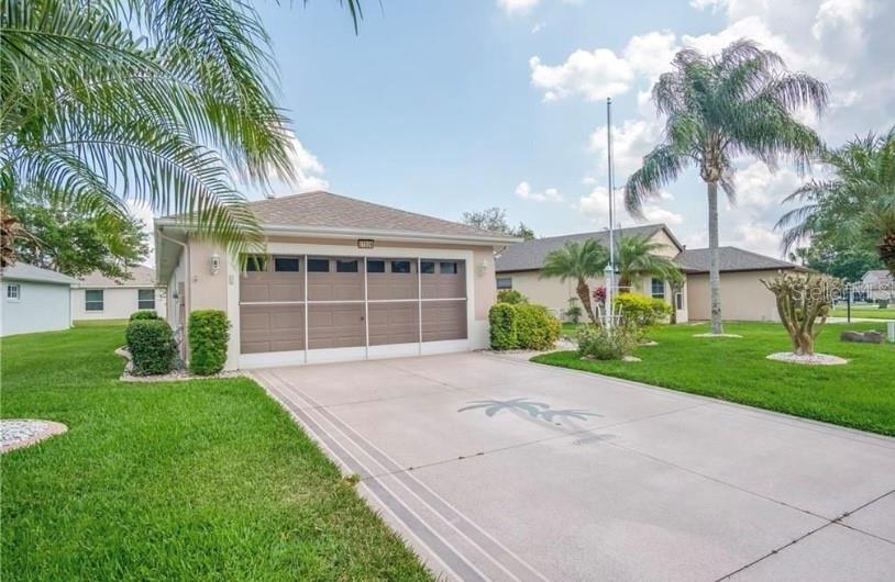 A single-story house with a beige garage door, a screened entryway, and a concrete driveway — 27326 ORCHID GLADE STREET, LEESBURG, FL