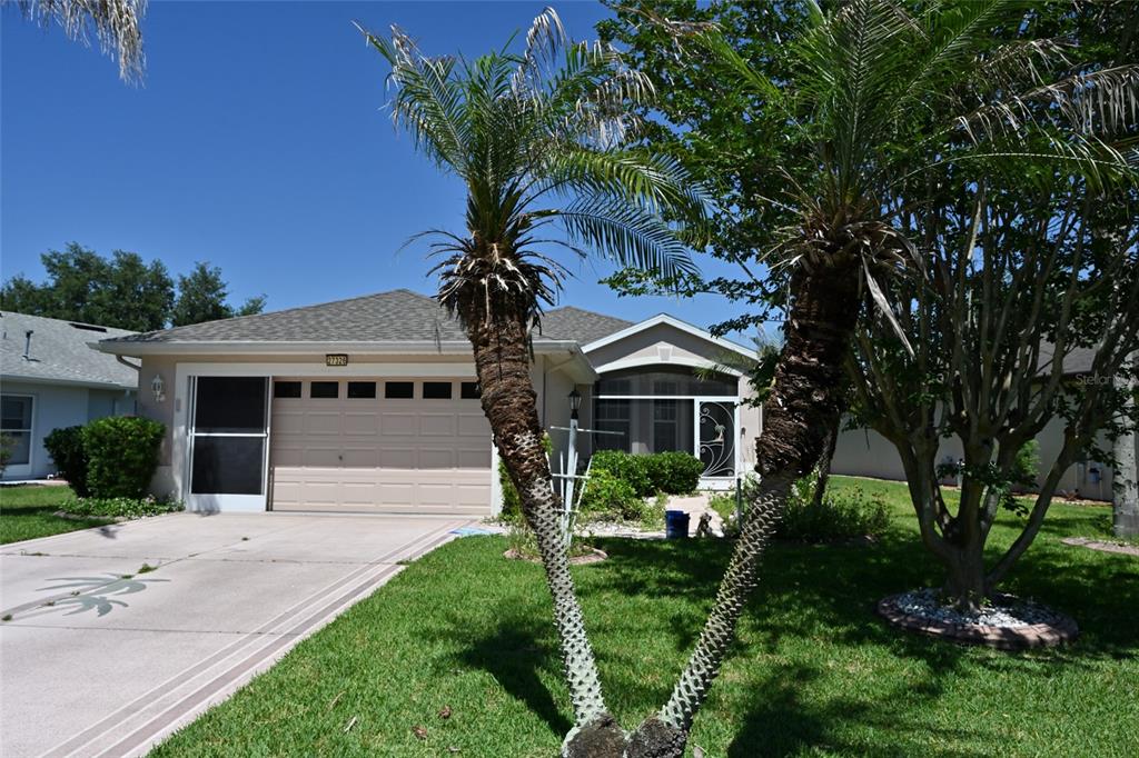 A concrete walkway leads to the screened front entrance of a house with palm trees — 27326 ORCHID GLADE STREET, LEESBURG, FL