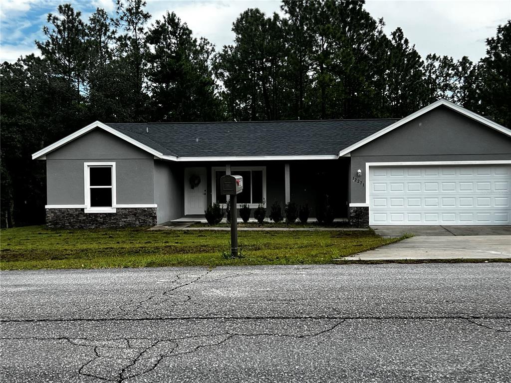 A single-story gray house with a stone base, white garage door, and dark shingled roof — 12271 SW 66TH STREET, OCALA, FL