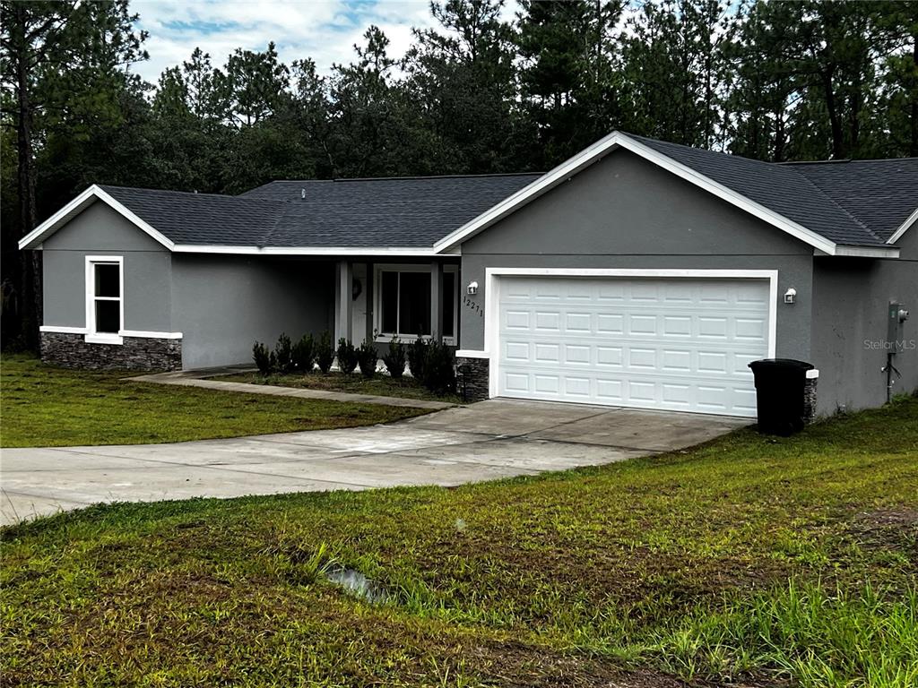 A gray single-story house with a white garage door and a stone-accented exterior wall — 12271 SW 66TH STREET, OCALA, FL