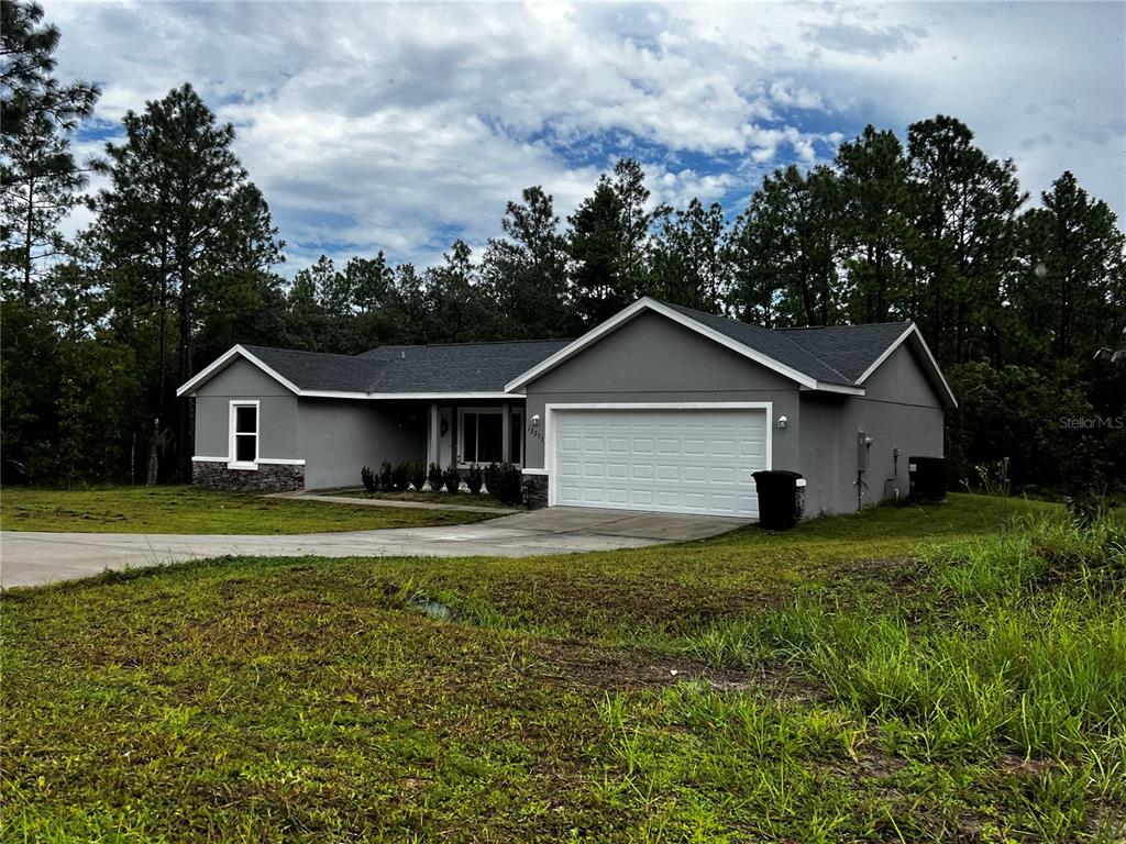 A single-story gray house with a two-car garage sits on a grassy lot with trees — 12271 SW 66TH STREET, OCALA, FL