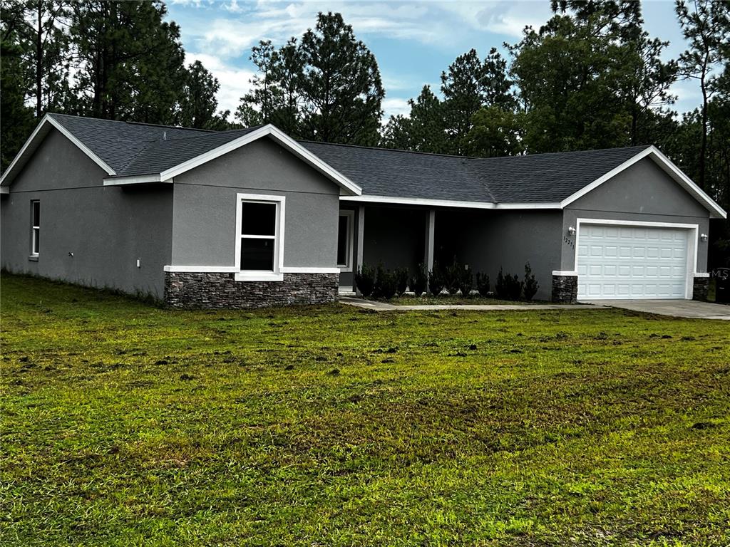 A gray single-story house with a stone base, white trim, and an attached two-car garage — 12271 SW 66TH STREET, OCALA, FL