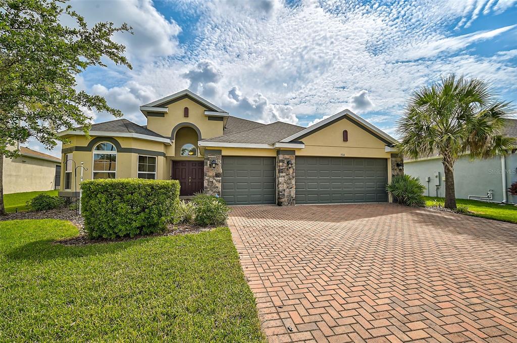 A single-story house with a brick paver driveway, two-car garage, and a palm tree — 5514 69TH PLACE E, ELLENTON, FL