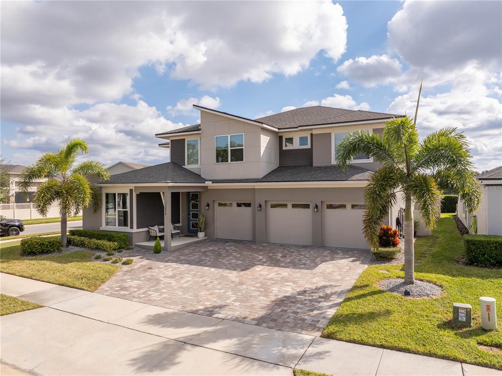A two-story house with a three-car garage, paved driveway, and palm trees in the front yard — 16894 WINGSPREAD LOOP, WINTER GARDEN, FL