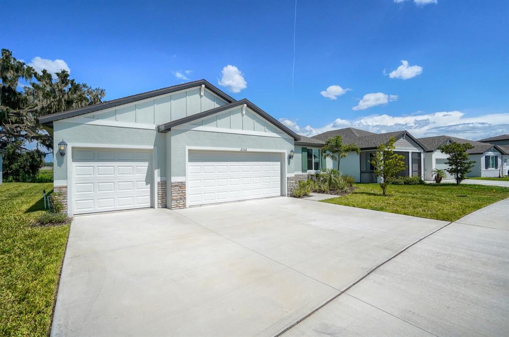 A light green single-story house with a three-car garage and a concrete driveway — 2332 CITRUS BLOOM DRIVE, BARTOW, FL