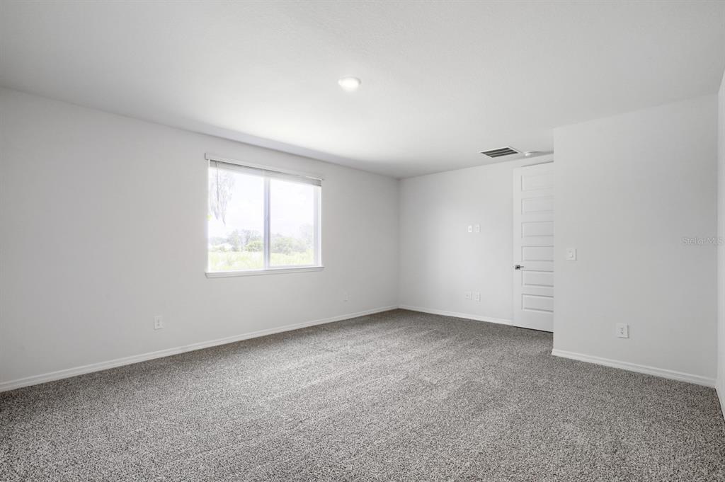 An empty bedroom with white walls, gray carpet, a single window, and a closed door — 2332 CITRUS BLOOM DRIVE, BARTOW, FL