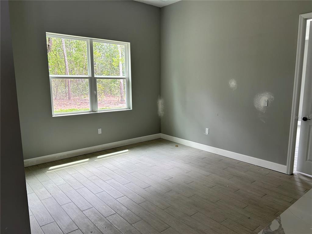 An empty room features gray walls, light-colored wood-look tile flooring, and a large window — 12 CACTUS STREET, HOMOSASSA, FL