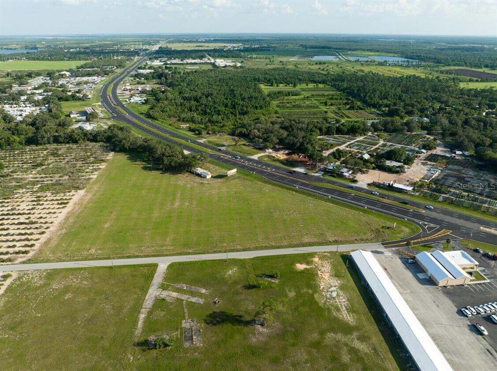 An aerial view shows a large grassy lot adjacent to a highway and commercial buildings — 4906 US HIGHWAY 27 S, SEBRING, FL