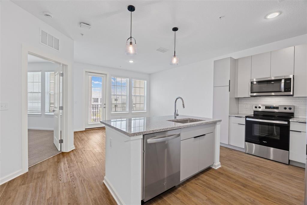 A modern kitchen features light gray cabinets, stainless steel appliances, and a granite-topped island — 1700 RANCH ROAD UNIT A4-7306, NOKOMIS, FL
